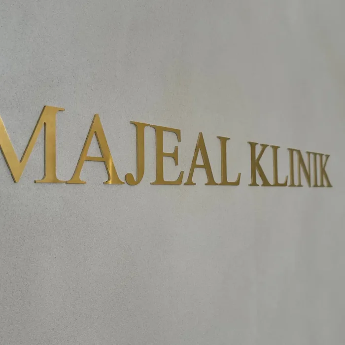 Elegant guldfärgad reklamskylt för Majeal Klinik i Stockholm, perfekt för en exklusiv och professionell inomhusmiljö.