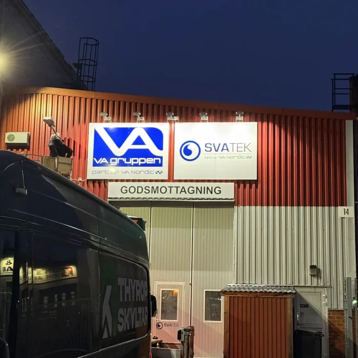 En ljusstark fasadskylt med företagsnamnen "VA Gruppen" och "SVATEK" på en industribyggnad. Ett tydligt exempel på lysande skylt LED för företag och lager.