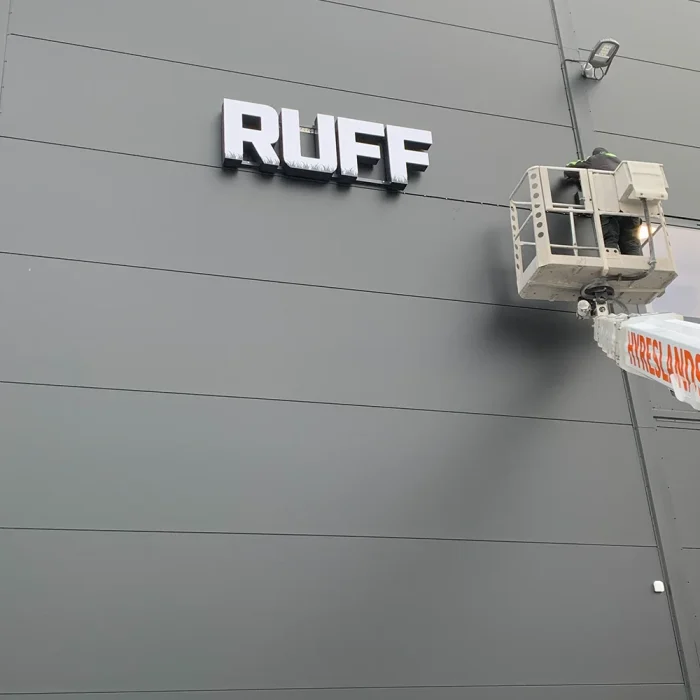 En svartvit skylt med texten "RUFF" monteras på en industribyggnad i Stockholm.