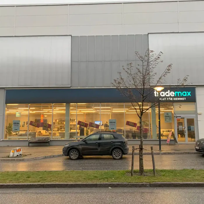 Fasadskylt för Trademax ovanför ett stort skyltfönster, med enkel men tydlig logotyp och LED-effekt – en funktionell fasadskylt företag för butikslokaler i handelsområden.