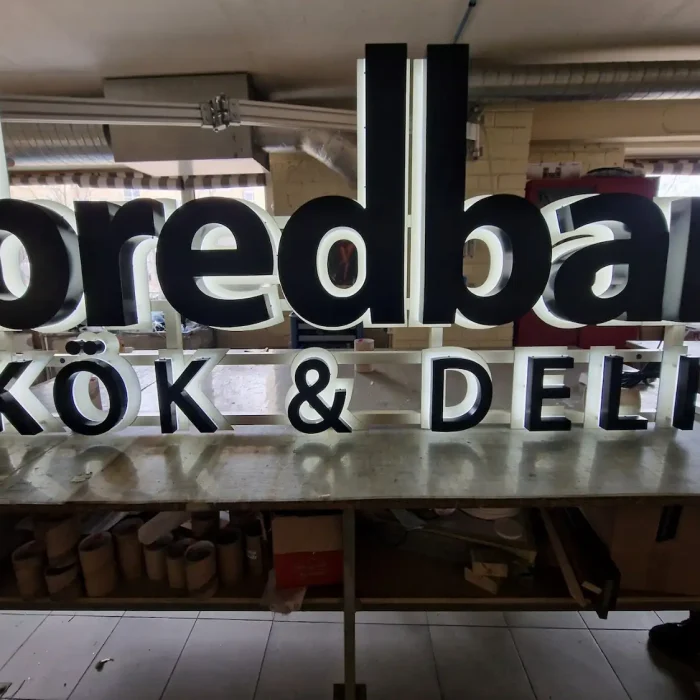 Belyst företagsskylt för restaurangen Bredbar – exempel på tydlig företagsskylt inomhus för kök & deli.