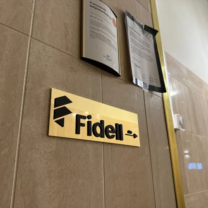 Inomhusskylt i mässing med svart logotyp, visar hur exklusiva plåtskyltar i Stockholm används i entrémiljöer för företag.