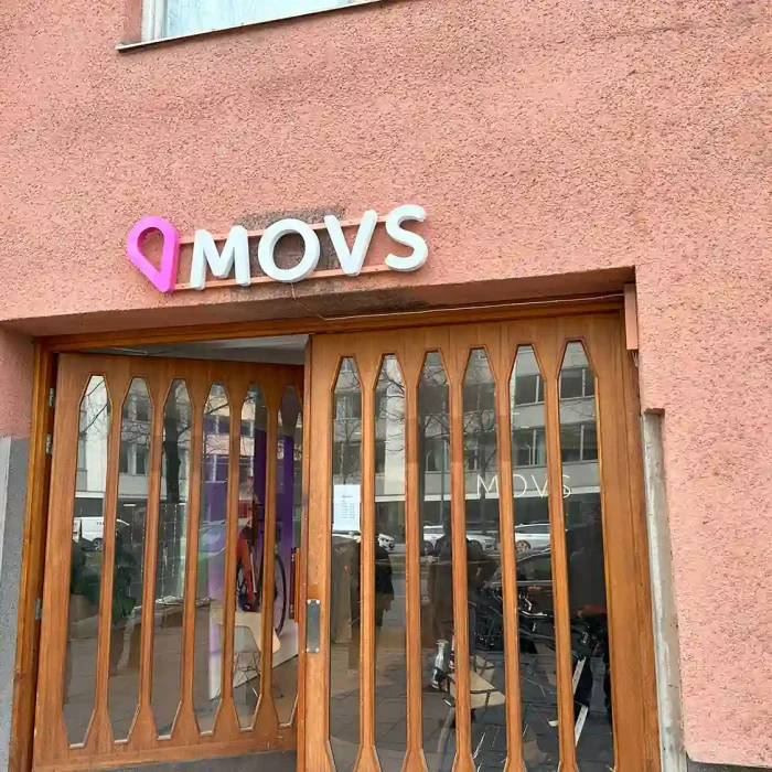 Logotyp i akryl ovanför träport för MOVS – färgstark identitet bland butiksskyltar i Stockholm